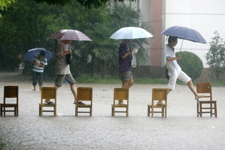 Chinese students make their way across a flooded school compound walking along a row of chairs, in Wuhan, in central China's Hubei province on June 18, 2011. (STR/AFP/Getty Images)