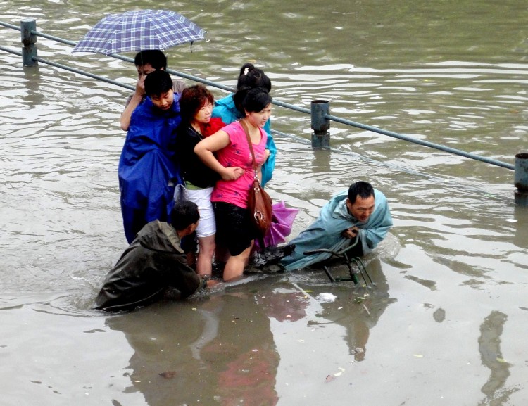 Pedestrians wade in a flooded street after heavy rainfall on June 18, 2011 in Wuhan, Hubei Province of China. (ChinaFotoPress/Getty Images)