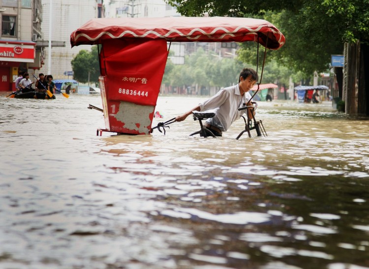 A man rides a bicycle through flood water in Lanxi, east China's Zhejiang province on June 20, 2011. (STR/AFP/Getty Images)