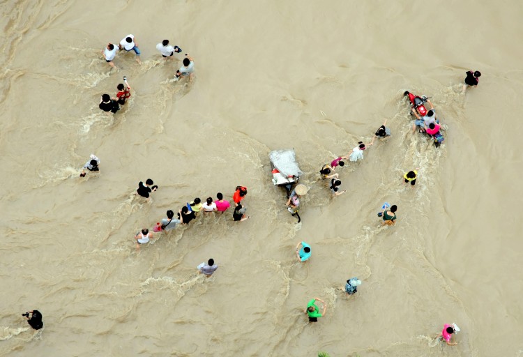 People make their way through flood water in Lanxi, east China's Zhejiang province on June 20, 2011. (STR/AFP/Getty Images)