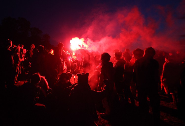 Festival goers gather around a lit flare at the Stone Circle at the Glastonbury Festival site. (Matt Cardy/Getty Images)