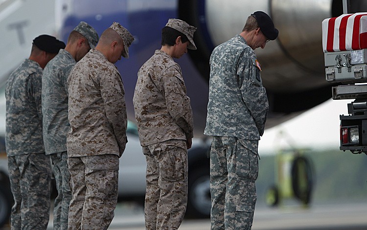 THE ULTIMATE SACRIFICE: Members of a transfer team bow their heads in respect for the remains of three U.S. service members during a dignified transfer ceremony on the tarmac at Dover Air Force Base June 30, in Dover, DE. (Win McNamee/Getty Images)