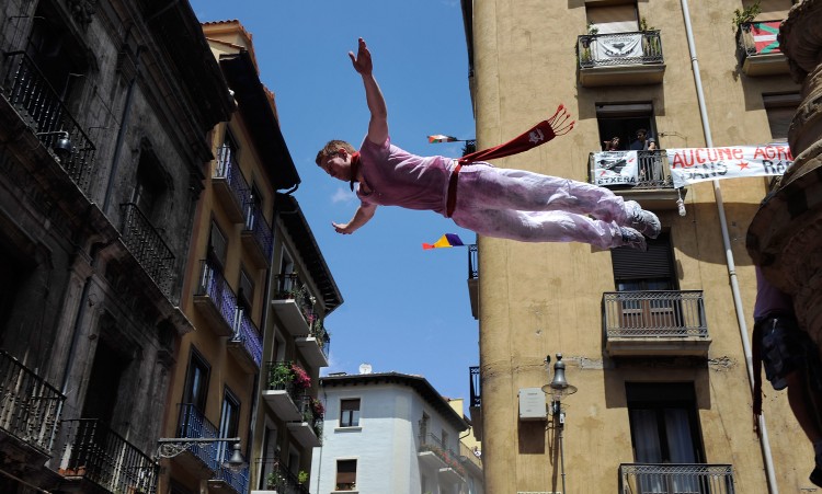 A festival goer jumps from a fountain to be caught by the crowd during the Chupinazo. (Dennis Doyle/Getty Images)