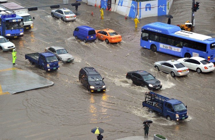 Cars drive through a flooded street after heavy rain in central Seoul on July 27, 2011.  (Jung Yeon-Je/AFP/Getty Images)