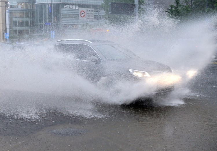 A car drives through a flooded street after heavy rain in central Seoul on July 27, 2011. (Jung Yeon-Je/AFP/Getty Images)