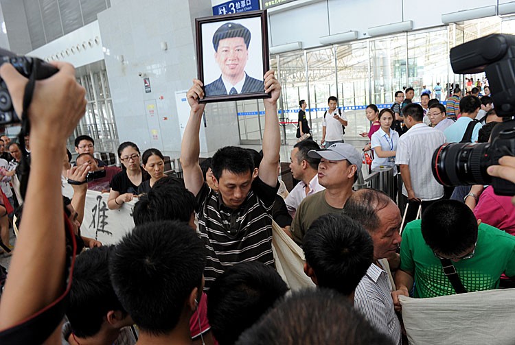 A Chinese man holds up a portrait of his relative as family members of victims who died in the July 23 high-speed train collision demonstrate in the hope of learning the truth about the train collision, at a railway station in Wenzhou, in eastern China's Zhejiang Province on July 27, 2011. One of China's official newspapers accused the authorities of 'arrogance' in their handling of the deadly high-speed train crash, joining a rising chorus of public fury.(STR/AFP/Getty Images)