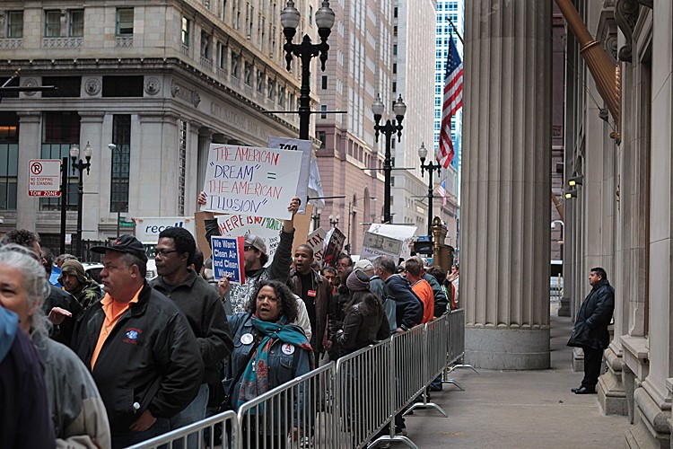 A security guard from the Bank of America building watches as demonstrators with Stand Up! Chicago march with supporters of Occupy Chicago in the financial district October 14, 2011 in Chicago, Illinois. The protest is one of many around the country held in solidarity with the Occupy Wall Street protests currently taking place in New York City.  (Scott Olson/Getty Images)