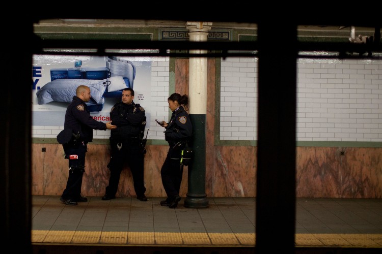 Three police officers stand guard inside the Wall Street subway station in New York City