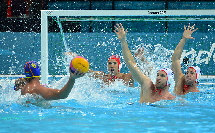 U.S. goalkeeper Merrill Moses (C) prepares to block a shot from Spain's Guillermo Molina Rios (L) while U.S. players Jeff Powers (2nd R) and Layne Beaubien prepare to block during the men's water polo semifinal at the London 2012 Olympic Games. (Adek Berry/AFP/GettyImages)