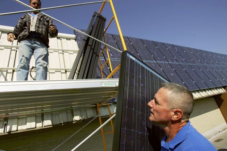 SUNSHINE AND CLEAN ENERGY: Workers install solar panels as part of a 256-panel system at the town hall in Hempstead, N.Y., in 2005. Panels are popping up with ever-increasing frequency all over the state, and new policies will further bolster the industry.   (Spencer Platt/Getty Images)