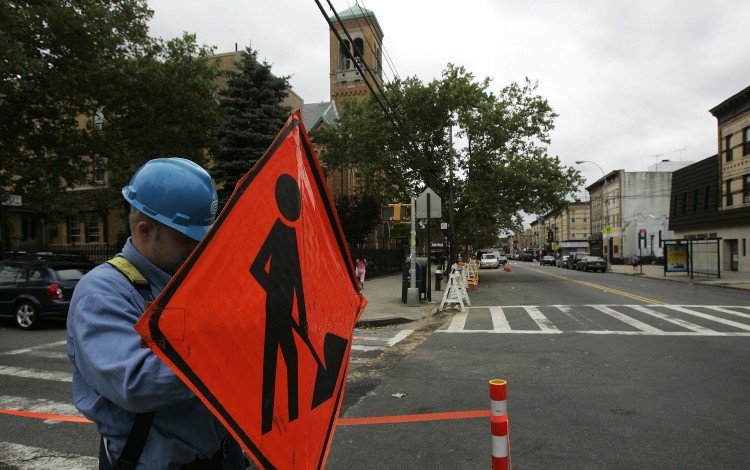 A Con Edison worker adjusts a sign as workers try to restore electrical service