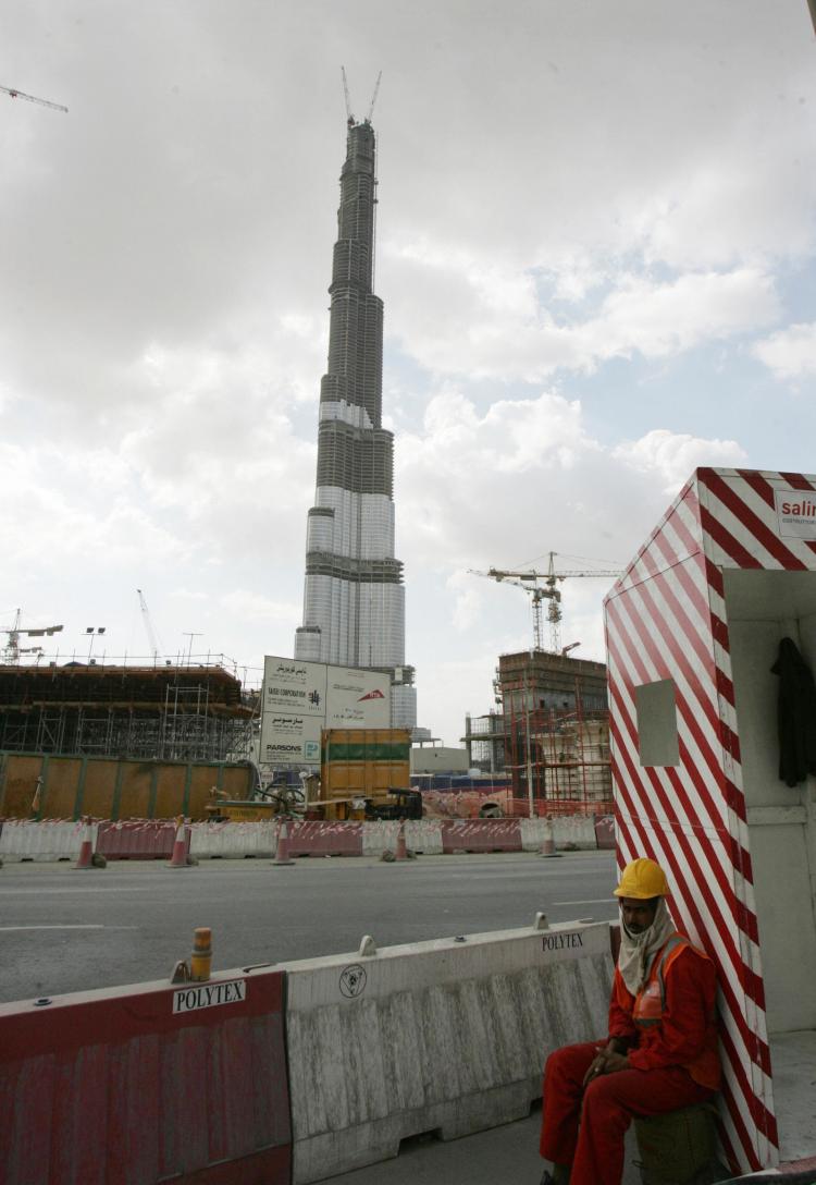 An Asian worker sits opposite Burj Dubai (C), in the Gulf emirate of Dubai, Jan. 9, 2008. Some 83 percent of the population of Dubai are expatriates, whose residency is dependent on the security of their jobs. (KARIM Karim Sahib/Getty Images)