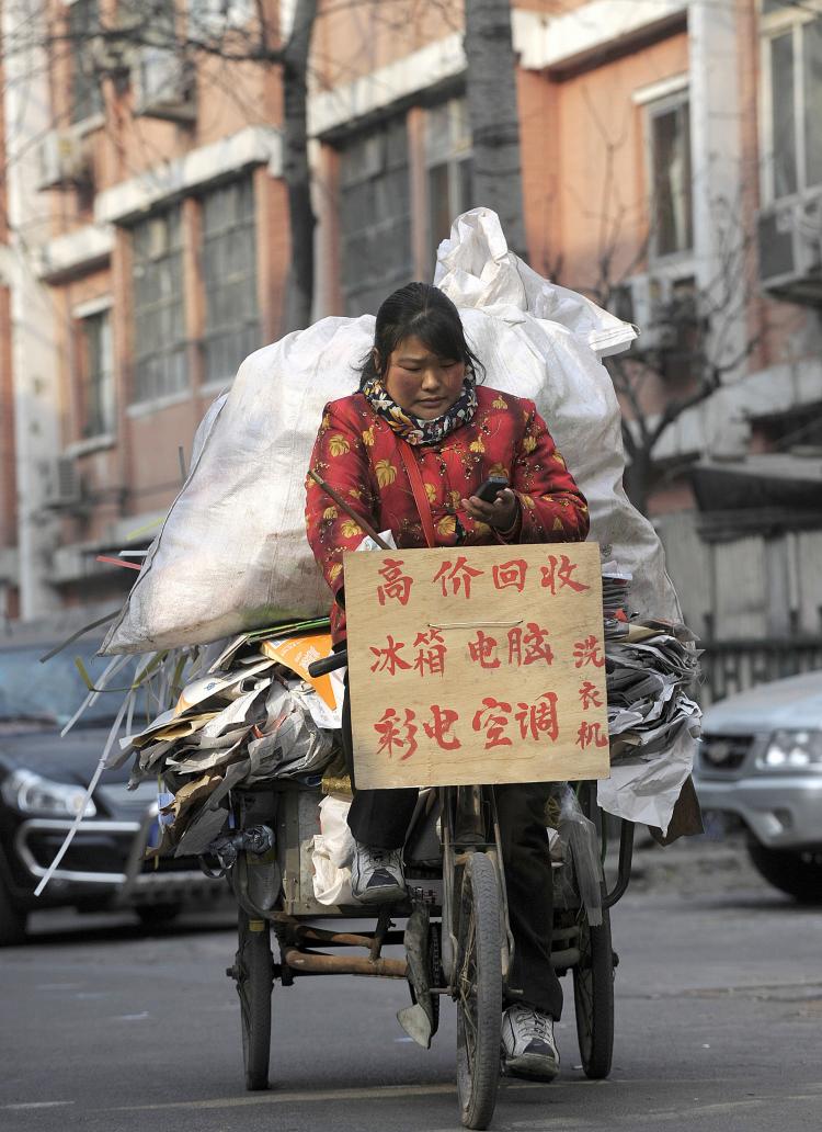 A woman rides a tricyle loaded with recyclable materials in Beijing. (Liu Jin/AFP/Getty Images)