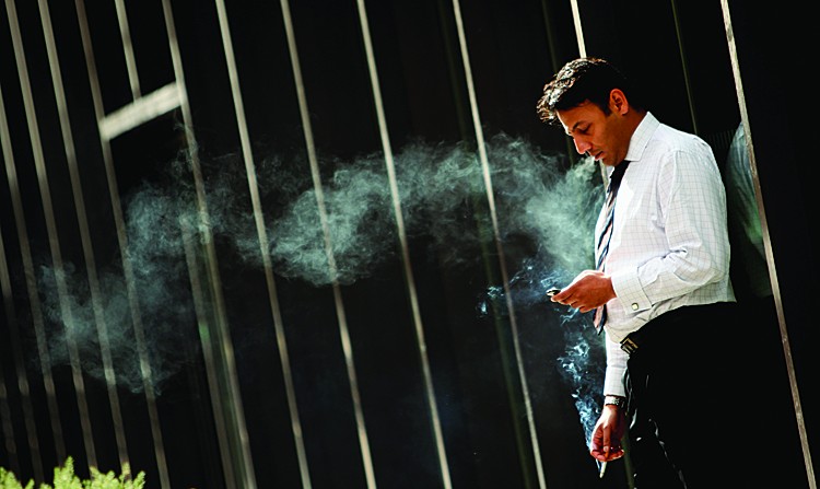 A worker smokes a cigarette outside an office building. Alberta has become the first province in Canada to dump its shares in tobacco companies and will soon launch a lawsuit to recoup smoking-related health care costs. (DAN KITWOOD/GETTY IMAGES)