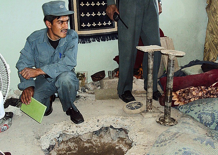 PRISON BREAK: An Afghan policeman sits next to the entrance of the tunnel in room number seven of the Political Prisoner's section through which Taliban fighters escaped in an audacious jailbreak from Kandahar prison in southern Kandahar city on April 25. (STR/AFP/Getty Images)