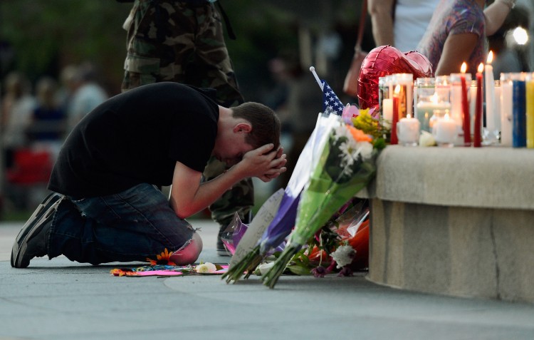 A mourner is seen in front of a makeshift memorial after a prayer vigil on July 22 for the victims of the mass shooting last week at the Century 16 movie theater in Aurora, Colo. (Kevork Djansezian/Getty Images)