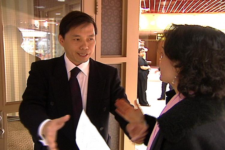 Reporter Danielle Zhu (R) being expelled from the event by an organizer, identified as Mr. Lu Kun, the acting consul general of the Chinese consulate in Toronto. Ms. Zhu is holding the invitation from the Chinese consulate. (Screen capture courtesy of New Tang Dynasty Television)