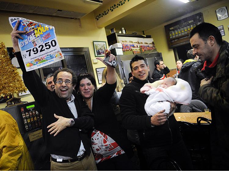 El Gordo winners celebrate as they hold up the winning number at the bar which sold the largest amount of winning tickets, Dec. 22 in Barcelona, Spain. (David Ramos/Getty Images)