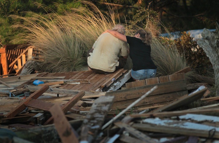 A man is comforted by a friend while he sits next to a pile of debris that was once his cottage, Aug. 28 in Nags Head, N.C. The cottage, built in 1903, was destroyed by Hurricane Irene.  (Scott Olson/Getty Images)