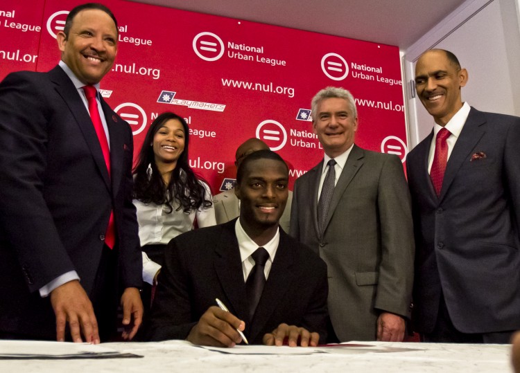 Former Giants wide receiver Plaxico Burress signs a pledge to promote anti-gun programs, participate in services that will help inform youths stay away from guns, and recruit other celebrities and athletes to join the cause. Coach Tony Dungy stands to the far right.  (Phoebe Zheng/The Epoch Times)