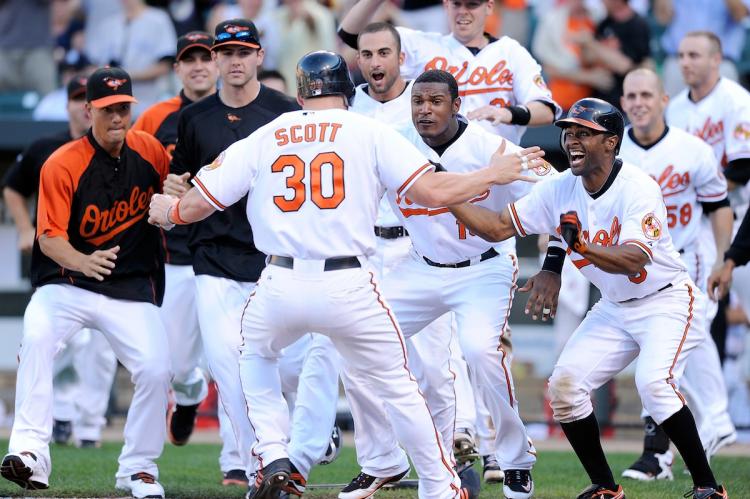CELEBRATION: Luke Scott of the Baltimore Orioles is cheered on by his teammates after scoring Sunday's 11th inning game-winning run against the New York Yankees.