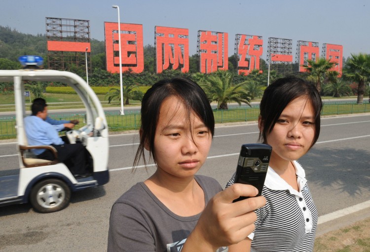 Chinese tourists stand in front of a large sign saying, 'One Country, Two Systems, the Same China,' a reference to communist China and democratic Taiwan's complicated relationship. (Mark Ralston/AFP/Getty Images)