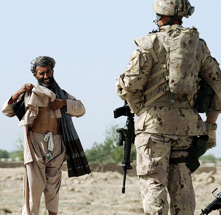 A Canadian soldier with the NATO-led International Security Assistance Force (ISAF) stops an Afghan passer-by during a patrol in Panjwayi district, some 30 kms west of Kandahar province earlier this year. The deaths of two children have brought Canadian s (Shah Marai/AFP/Getty Images)