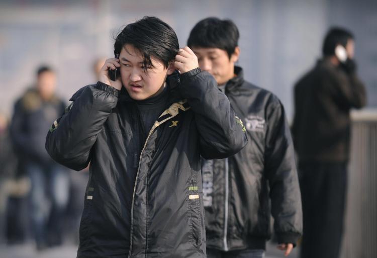 Cell phone virus affects a million: People use mobile phones on a street in Beijing on January 7, 2009. (Peter Parks/AFP/Getty Images)