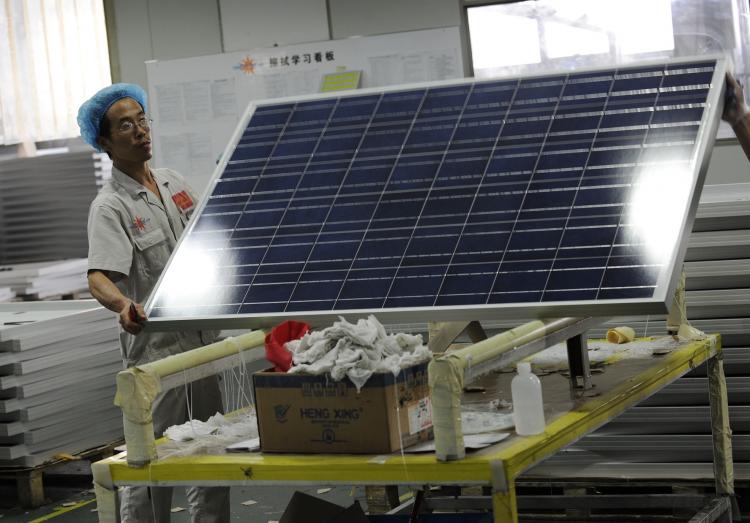 China's clean energy policies are being investigated by US trade officials. Above, a worker lifts a solar panel in the Yingli Solar factory, in Baoding, Hebei province, China in September. (PETER PARKS/AFP/Getty Images)