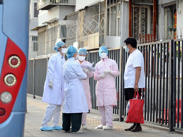 Chinese medical personnel check the Beijing neighborhood near a hostel where a group of school children are quarantined after seven people in their school were diagnosed with the swine flu, July 2, 2009. (AFP/Getty Images)