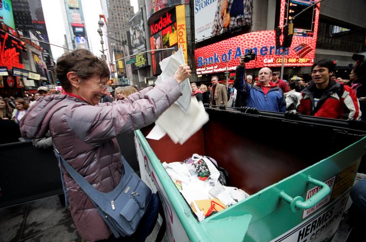 GOOD RIDDANCE: A New York woman is relieved and happy as she disposes of some bad news from the past year at the 'Good Riddance Day' ceremony on Times Square on Sunday. (Edward Dai/The Epoch TImes)