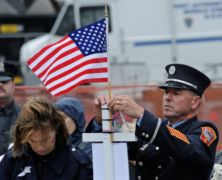 A firefighter posts a small American flag as he pays his respects at Ground Zero during a 9/11 memorial ceremony on September 11, 2009 in New York City. (Peter Foley-Pool/Getty Images)