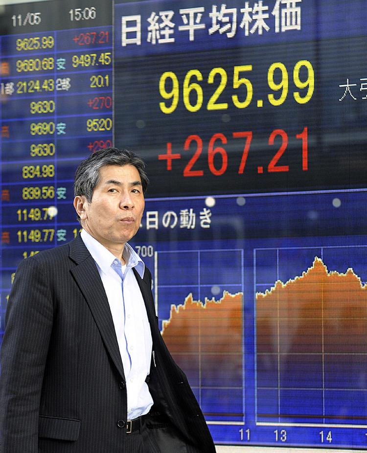 ECONOMIC REBOUND: A man passes before a share prices board in Tokyo earlier this month. Japan's third-quarter GDP grew at a faster pace than anticipated. (Yoshikazu Tsuno/AFP/Getty Images)