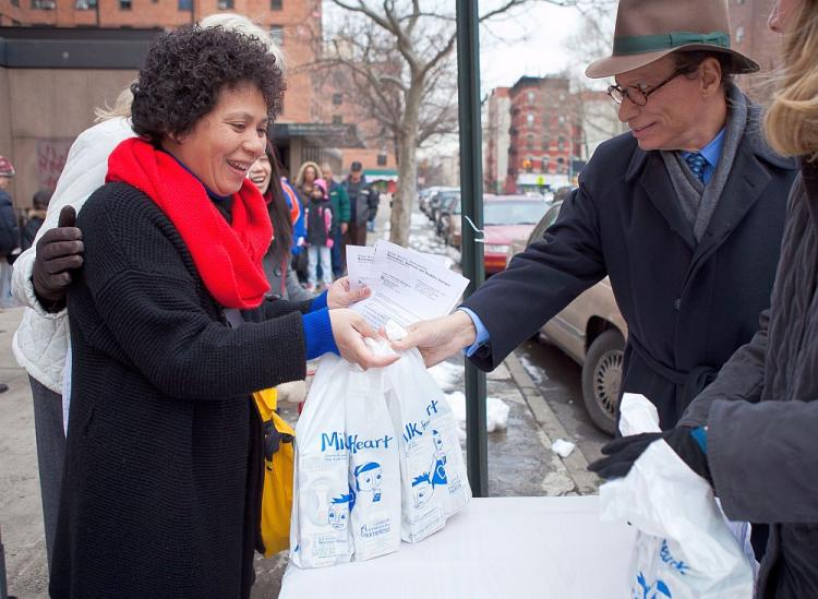 MILK FROM THE HEART: Leonard Stern (R) hands out milk outside the Boys and Girls Republic on Sixth Street in Manhattan on Thursday. (Amal Chen/The Epoch Times)