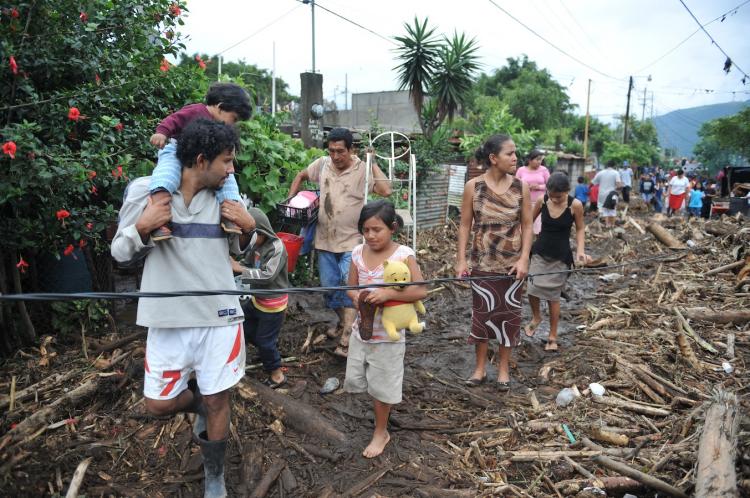 People walk next to the ruins of their homes, destroyed by tropical strom Agatha, on May 30, in the village of Los Almendros, 39 km south of Guatemala City. The first tropical storm of the season has left at least 18 people dead.  (Johan Ordonez/Getty Images)