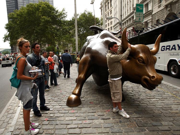 Tourists pose with the Wall St. bull in the financial district in New York City, September 16, 2008.   (Spencer Platt/Getty Images)