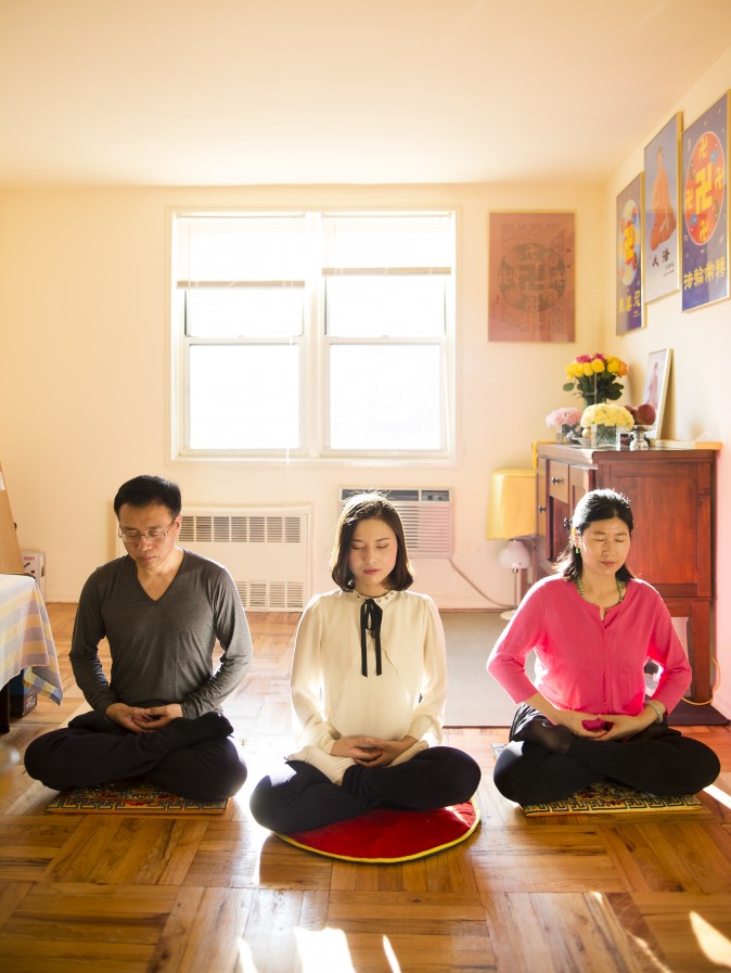 (L-R) Li Zhenjun, Li Fuyao e Wang Huijuan demonstram sua prática de meditação em sua casa em Queens, Nova Iorque, em 8 de janeiro de 2016. Eles fugiram da China em 2014 e receberam asilo após anos de tortura por praticar o Falun Gong (Samira Bouaou / Epoch Times)