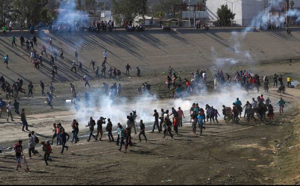 Migrants run from tear gas, thrown by the U.S. border patrol,