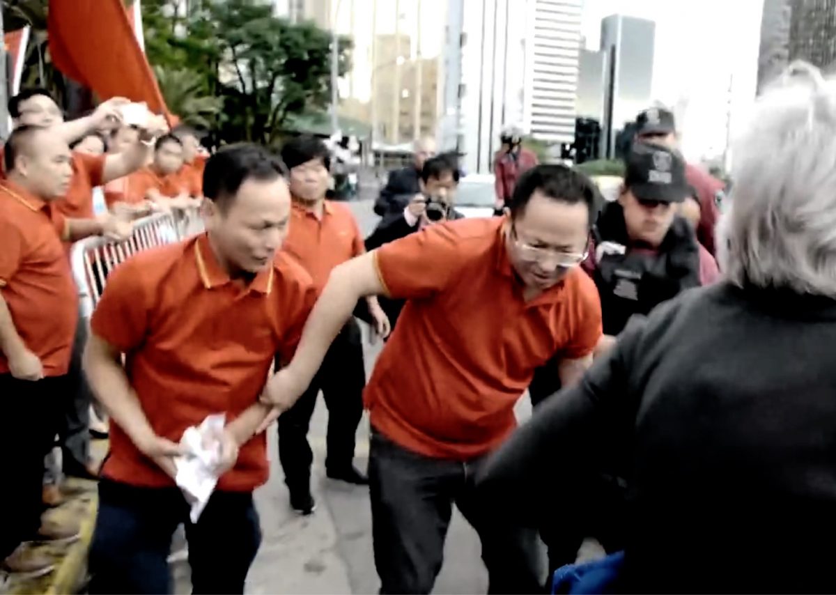 Os partidários do Partido Comunista Chinês pegam e agitam os panfletos que estavam dentro de uma bolsa de um praticante do Falun Gong que caiu no chão em 29 de novembro em Buenos Aires, Argentina (Screenshot / via YouTube)