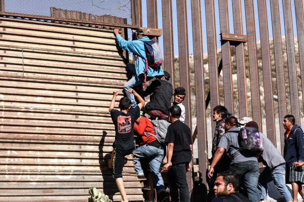 Migrantes atravessam a cerca da fronteira dos Estados Unidos logo depois da entrada leste de pedestre da travessia de San Ysidro, em Tijuana, México, em 25 de novembro de 2018 (Charlotte Cuthbertson / The Epoch Times)