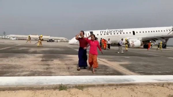 Passengers walk away from the plane after Myanmar National Airlines flight UB103 landed without a front wheel at Mandalay International Airport in Tada-u