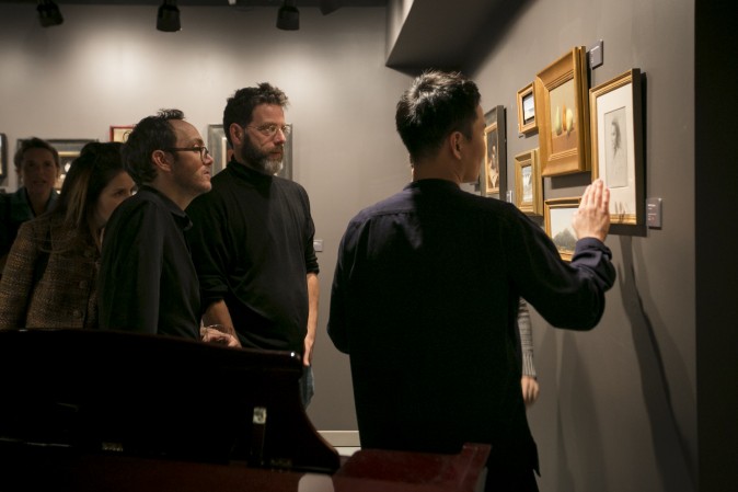 Artists, Dale Zinkowski (L) Patrick Byrnes (R) and founder of Grand Central Atelier, Jacob Collins (C), look at artwork at the opening of the Wrap Me Up: Winter Small Works Show at Eleventh Street Arts gallery in Long Island City, New York, on Nov. 17, 2016. (Samira Bouaou/Epoch Times)