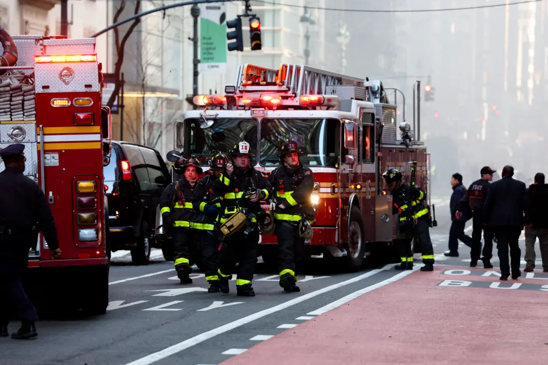 Firefighters from New York Fire Department (NYFD) work at the scene as fire and heavy smoke are seen at a high-rise building in Midtown Manhattan near the St. Patrick's Day Parade route in New York City on March 17, 2026. (Photo by TIMOTHY A. CLARY / AFP via Getty Images)