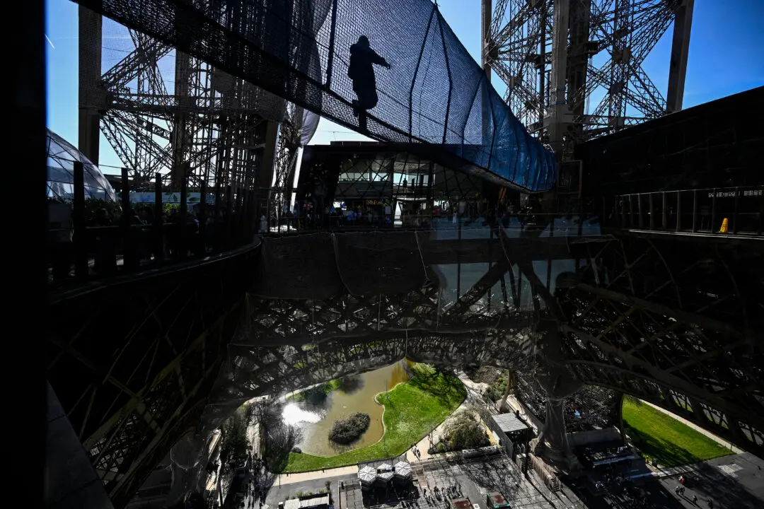 TOPSHOT - A visitor walks on the "Le vertige de la Tour" ("The vertigo of the tower") suspension bridge on the first floor of the Eiffel Tower, which connects the east and west pillars at a height of nearly 60 meters, in Paris on March 17, 2026. (Photo by JULIEN DE ROSA / AFP via Getty Images)