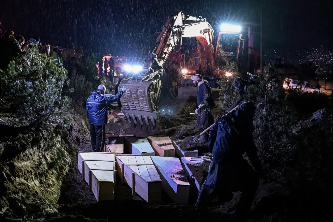 Volunteers place coffins of victims who were killed in a Pakistani air strike on a drug rehabilitation centre, into a mass grave during a burial ceremony at the Badam Bagh Hilltop in Kabul, Afghanistan, on March 18, 2026. The Taliban authorities have said that around 400 people were killed and more than 200 wounded on March 16 night, in the deadliest attack yet in the recent upsurge in violence between the two neighbours. (Wakil Kohsar / AFP via Getty Images)
