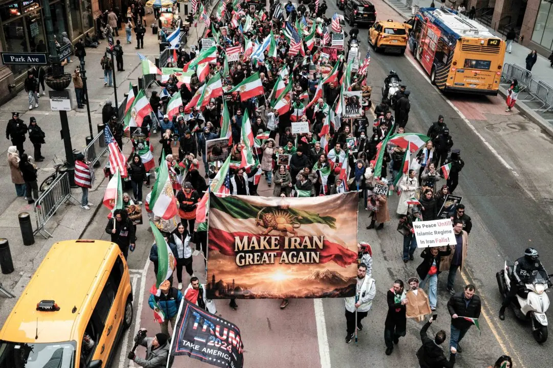 People carry a sign reading "Make Iran Great Again" and wave pre-revolutionary Iranian, US and Israeli flags as they march along 42nd Street to support regime change in Iran, in New York City on March 15, 2026. (Charly Triballeau / AFP via Getty Images)