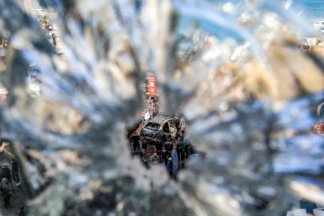 Civil defence members gather around a destroyed vehicle that was targeted by Israeli bombardment in Sidon, Lebanon, on March 18, 2026. Lebanon was drawn into the Middle East war on March 2 when pro-Iran Hezbollah launched rockets towards Israel in response to US-Israeli strikes that killed Iran's supreme leader. (Mahmoud Zayyat / AFP via Getty Images)